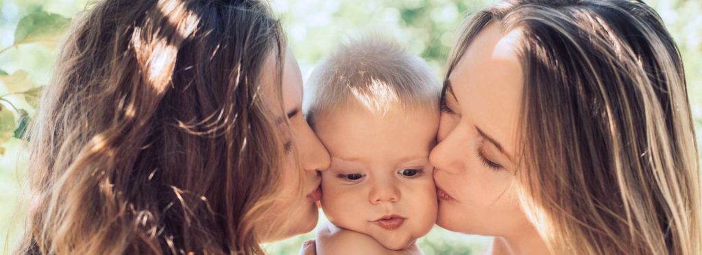lesbian couple kissing their daughter